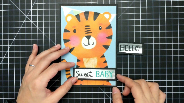 Handmade greeting card with large tiger on the front. Two hands are shown placing a sentiment strip that reads "Sweet Baby"